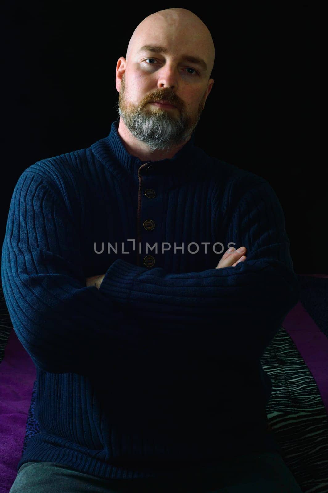 Well dressed caucasian male, late thirties, in dark clothes on dark background. Studio shot with side lighting, low key portrait