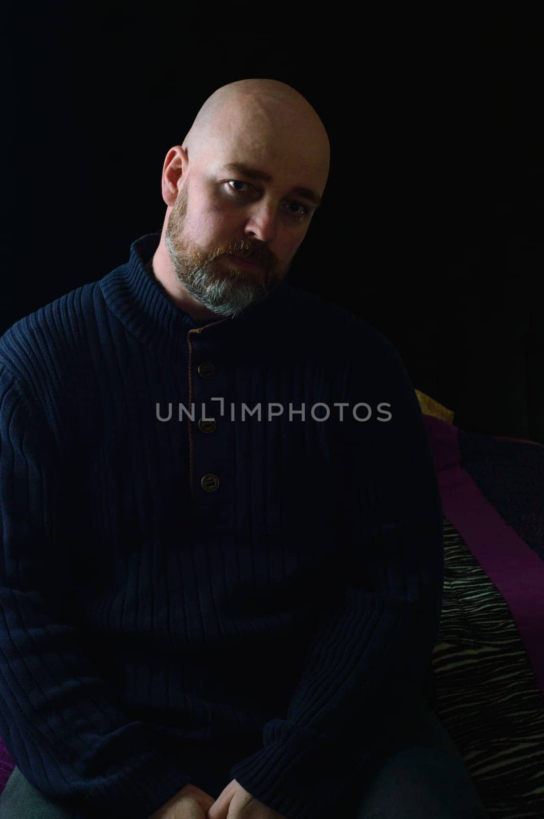 Well dressed caucasian male, late thirties, in dark clothes on dark background. Studio shot with side lighting, low key portrait