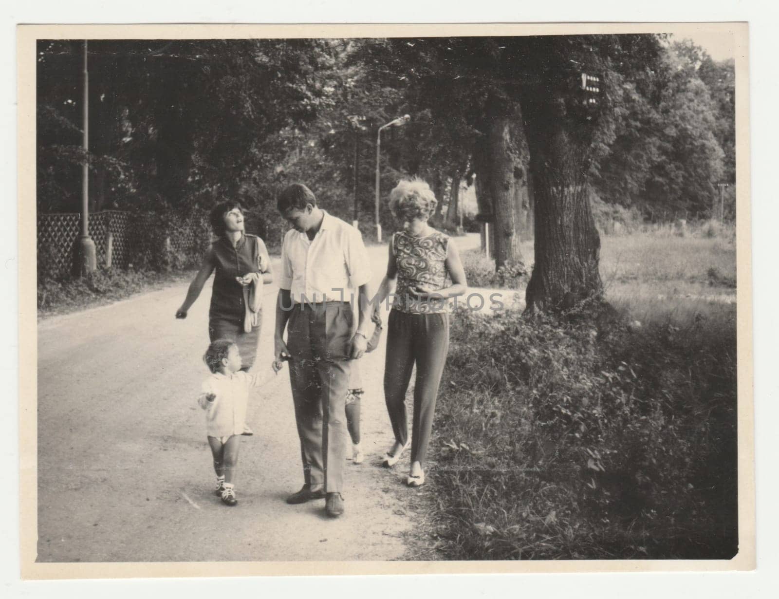 Vintage photo shows people go for a walk. Retro black and white photography. Circa 1980. by roman_nerud