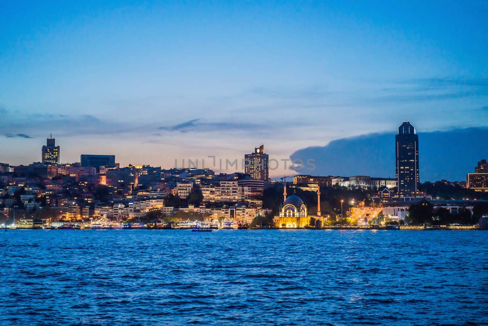 Istanbul at sunset, Turkey. Tourist boat sails on Golden Horn in summer. Beautiful sunny view of Istanbul waterfront with old mosque. Concept of travel, tourism and vacation in Istanbul and Turkey. Turkiye.