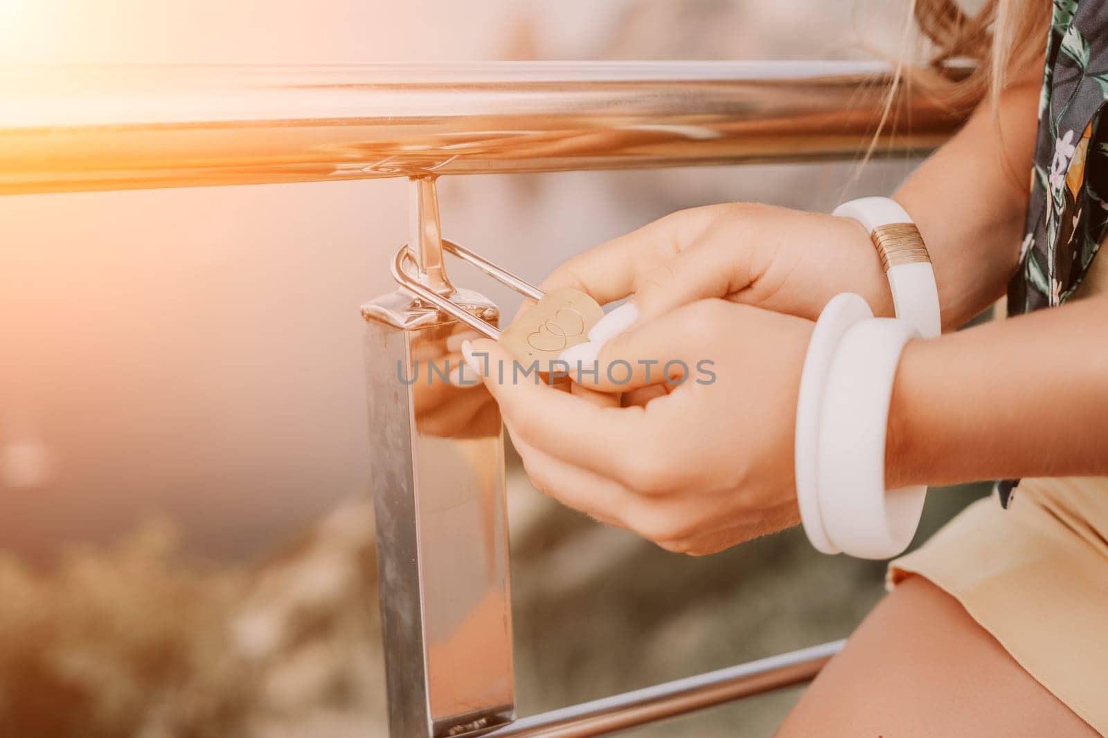 Hand, lock, heart, love, valentines day. Close up view of a woman holding a heart shaped lock that is locked onto a chain link fence.