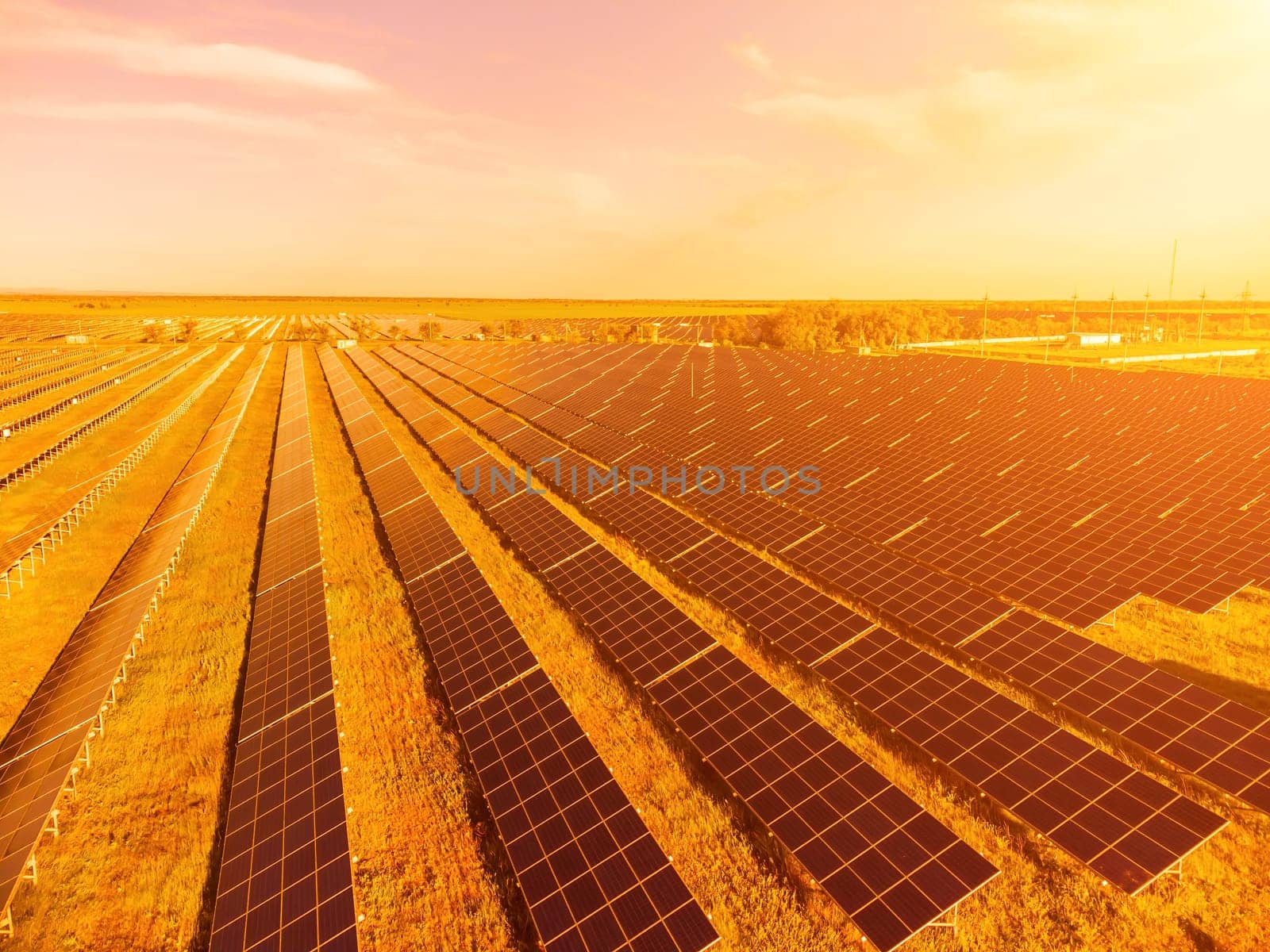 Aerial top view of a solar panels power plant. Photovoltaic solar panels at sunrise and sunset in countryside from above. Modern technology, climate care, earth saving, renewable energy concept. by panophotograph