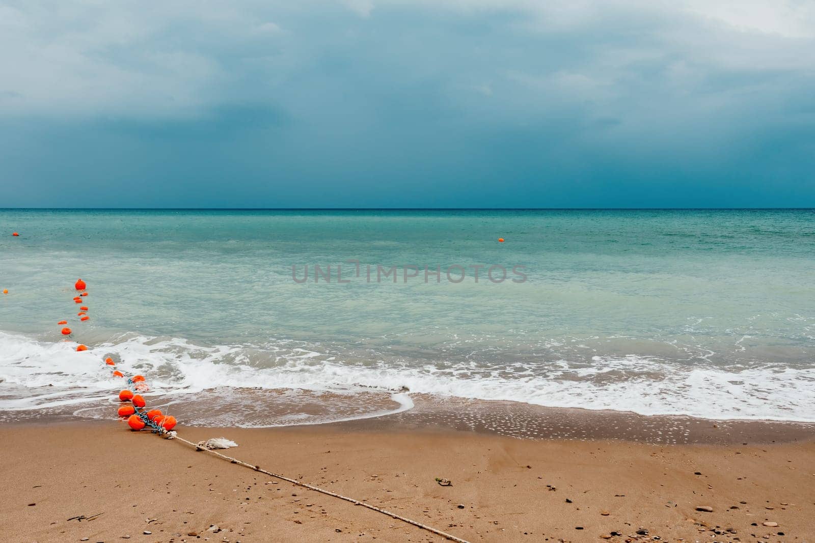 Overcast sky on rainy day with foamy waves rolling towards golden sand beach under low warm sun light. Nobody. Holiday recreation concept. Abstract nautical summer ocean sunset nature. by panophotograph