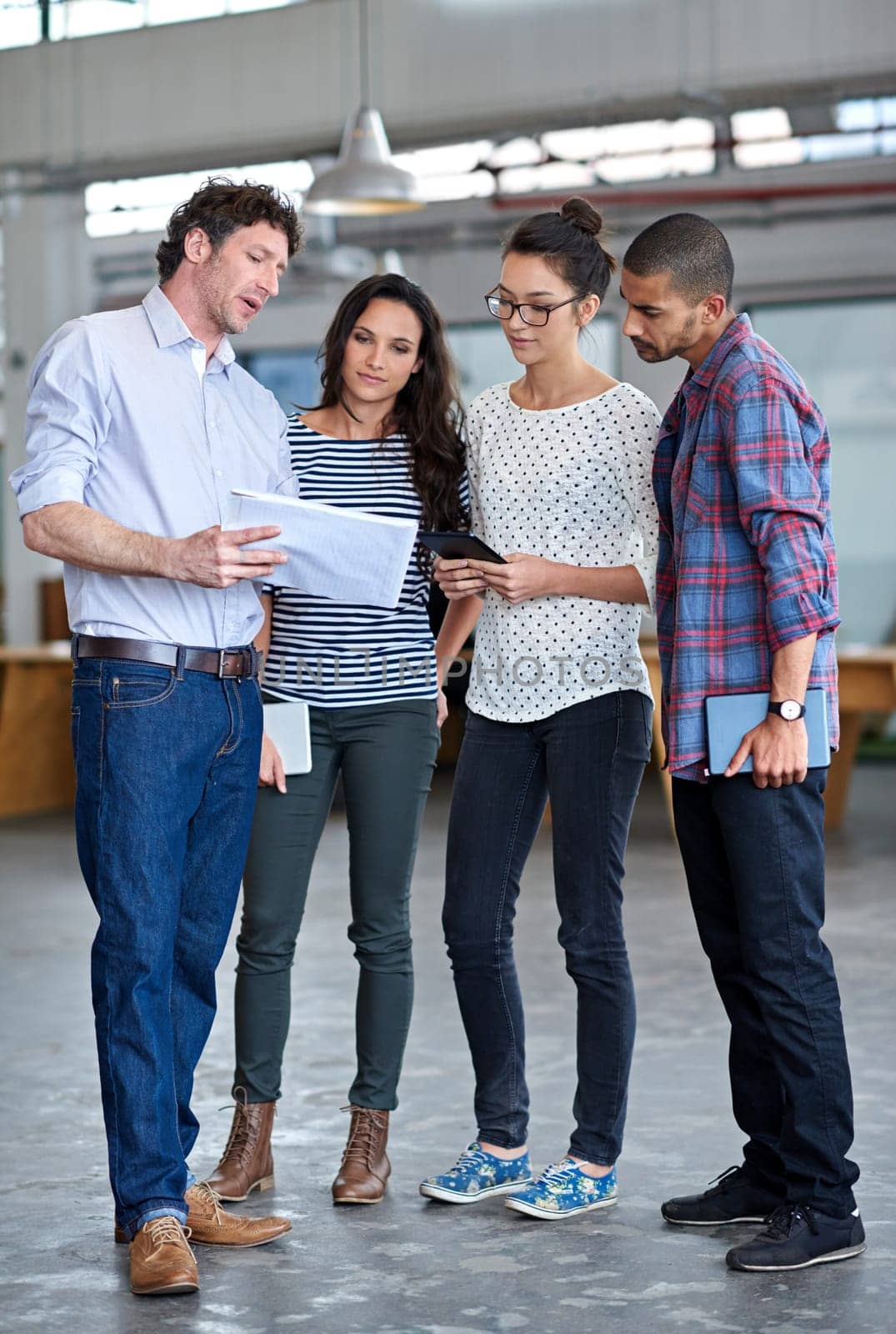 Putting their heads together for a quick meeting. Group of staff discussing something while standing in their office space