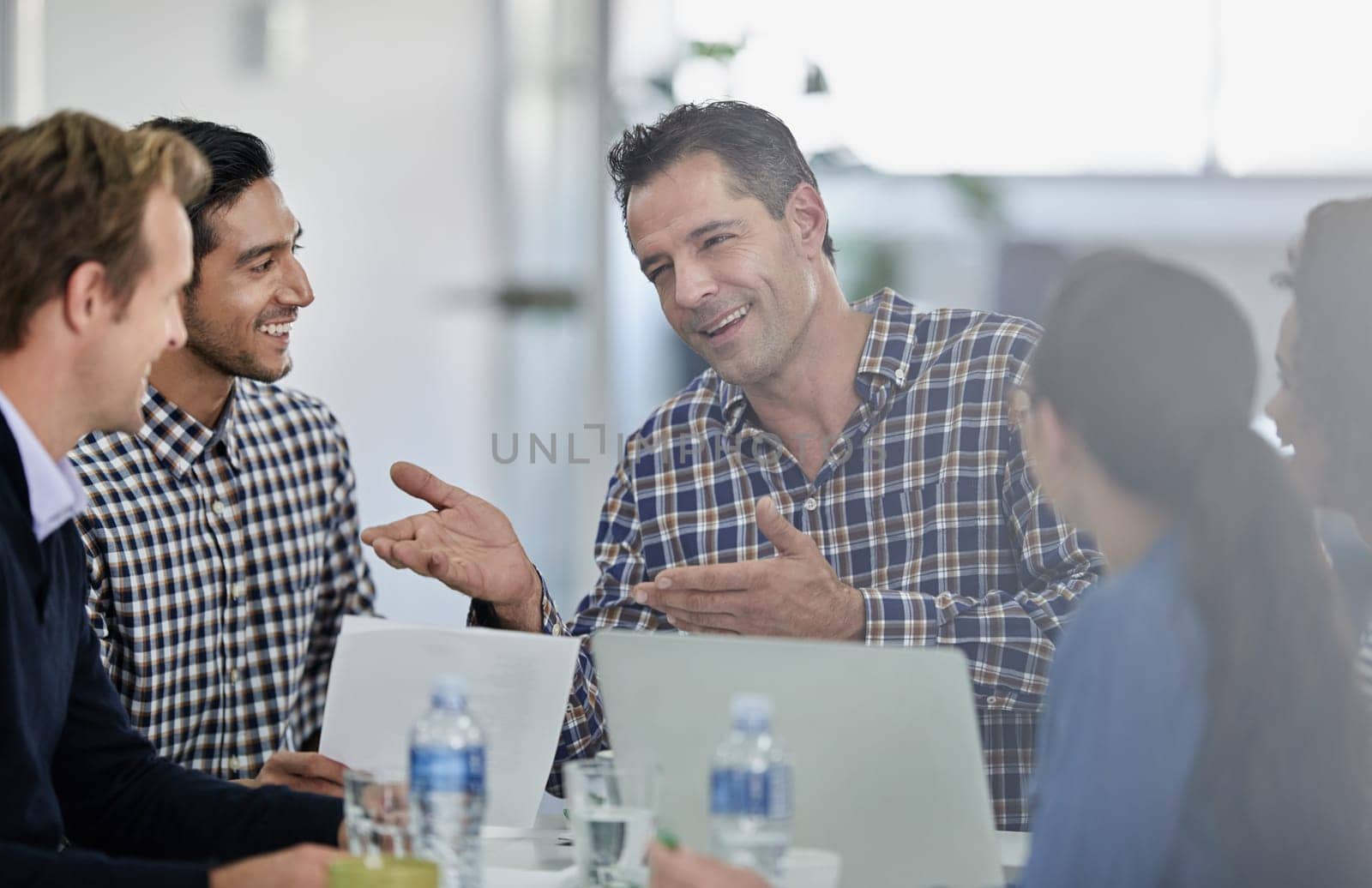 Hes a great communicator. Group of colleagues sitting round a meeting table having a discussion. by YuriArcurs