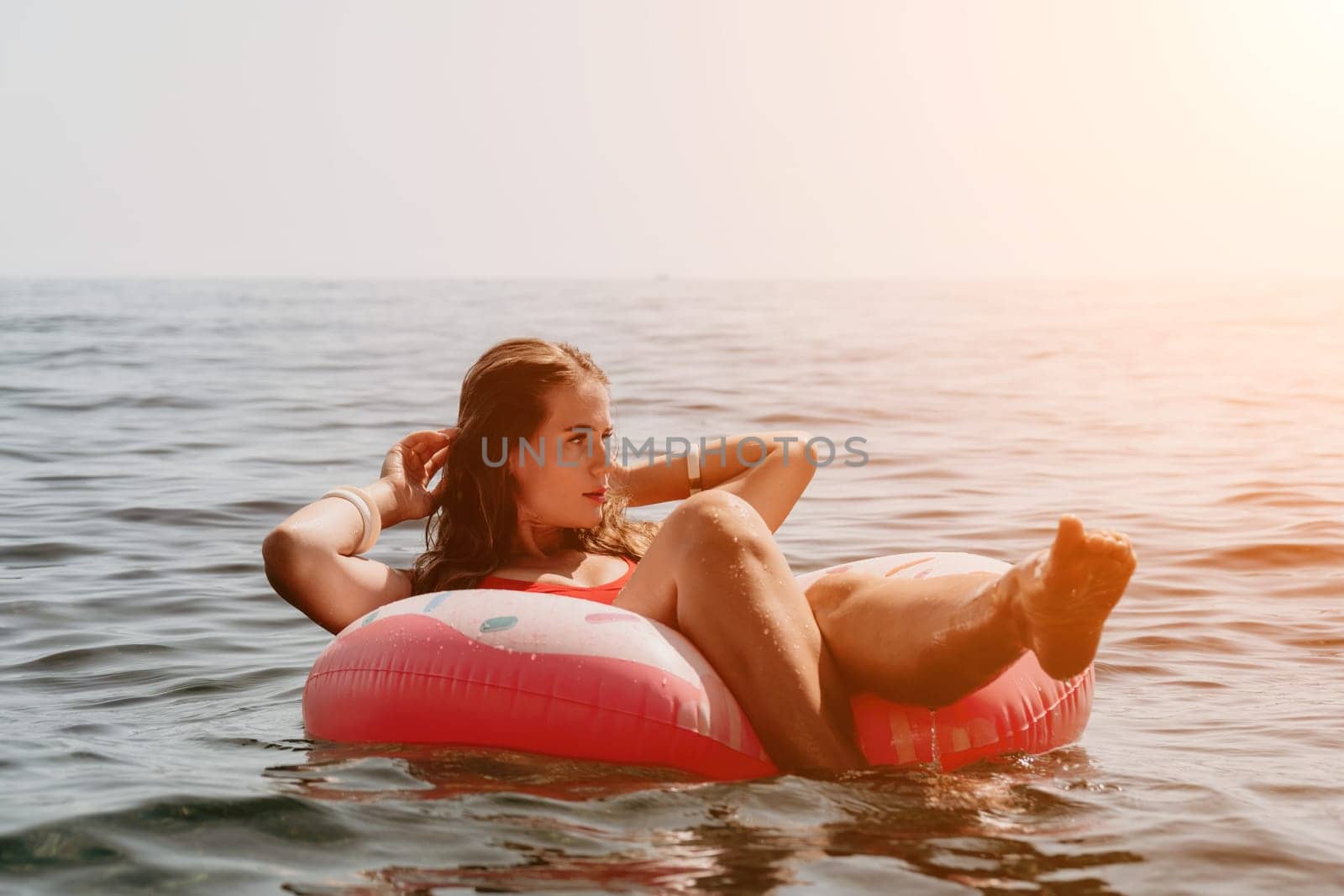 Woman summer sea. Happy woman swimming with inflatable donut on the beach in summer sunny day, surrounded by volcanic mountains. Summer vacation concept