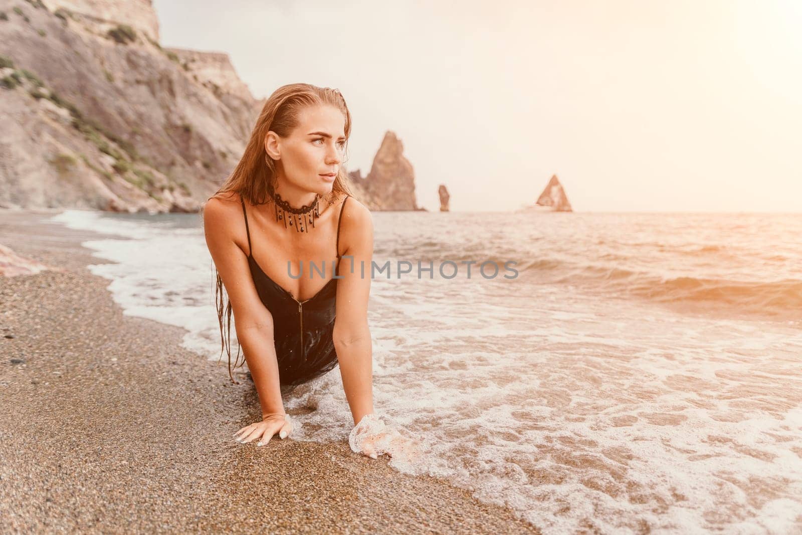 Woman travel sea. Young Happy woman in a long red dress posing on a beach near the sea on background of volcanic rocks, like in Iceland, sharing travel adventure journey