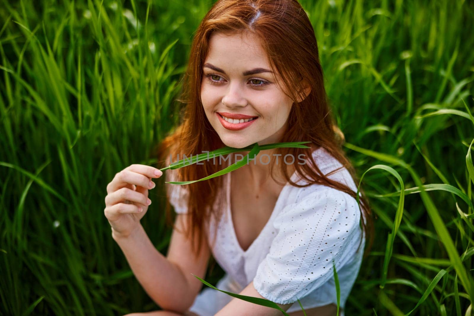 portrait of a happy, laughing woman sitting in tall grass in a field. High quality photo