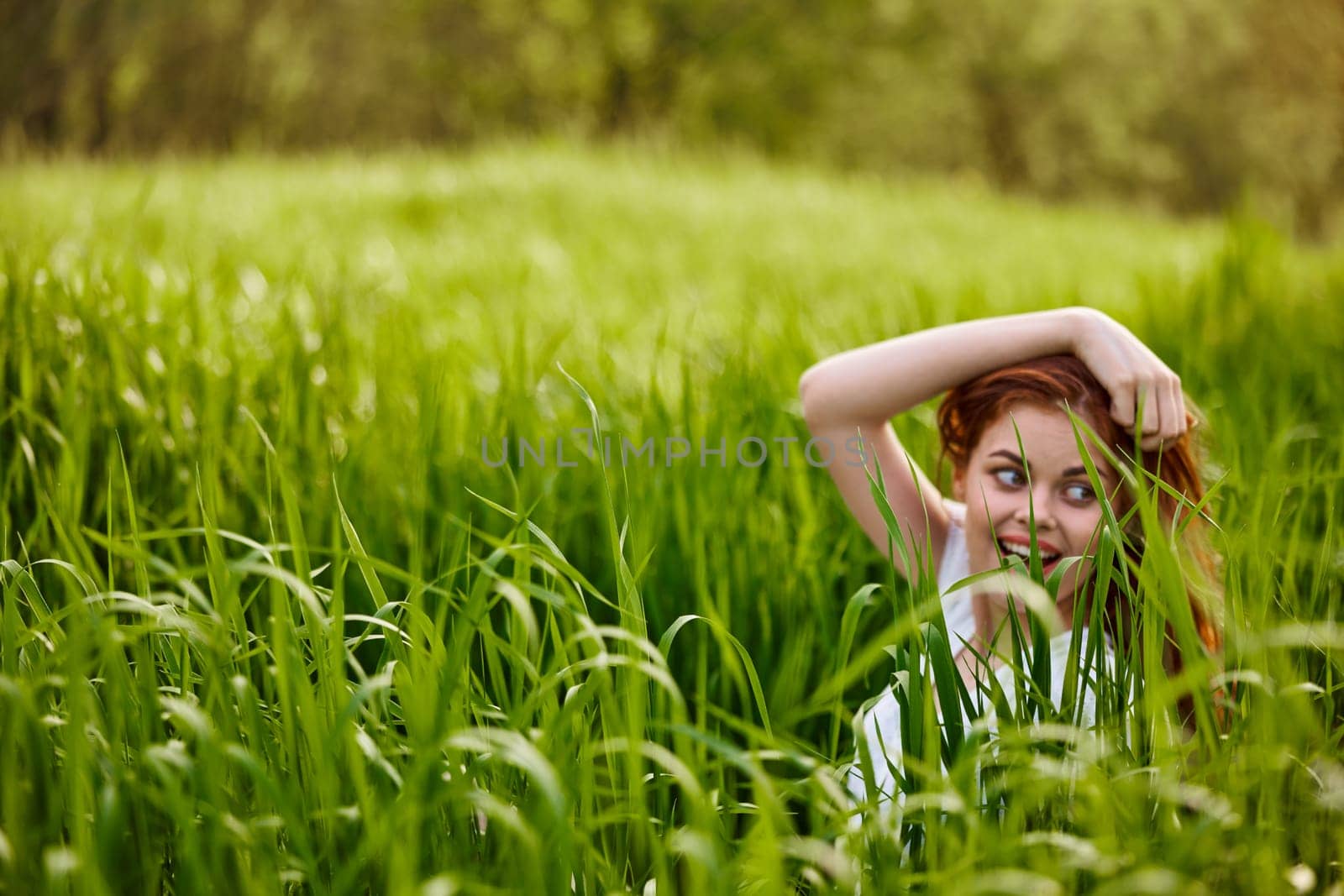 happy woman sitting in tall green grass holding her hair. High quality photo