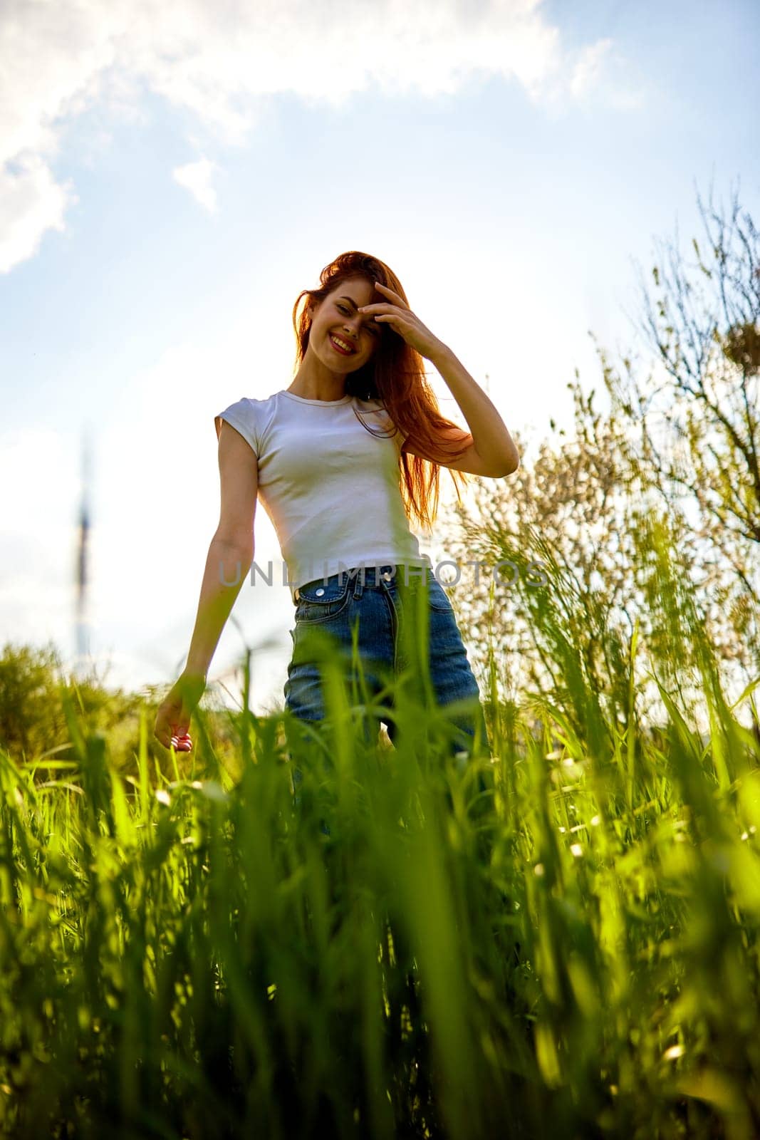 cute woman in summer clothes standing in a field of tall grass, bottom view. High quality photo