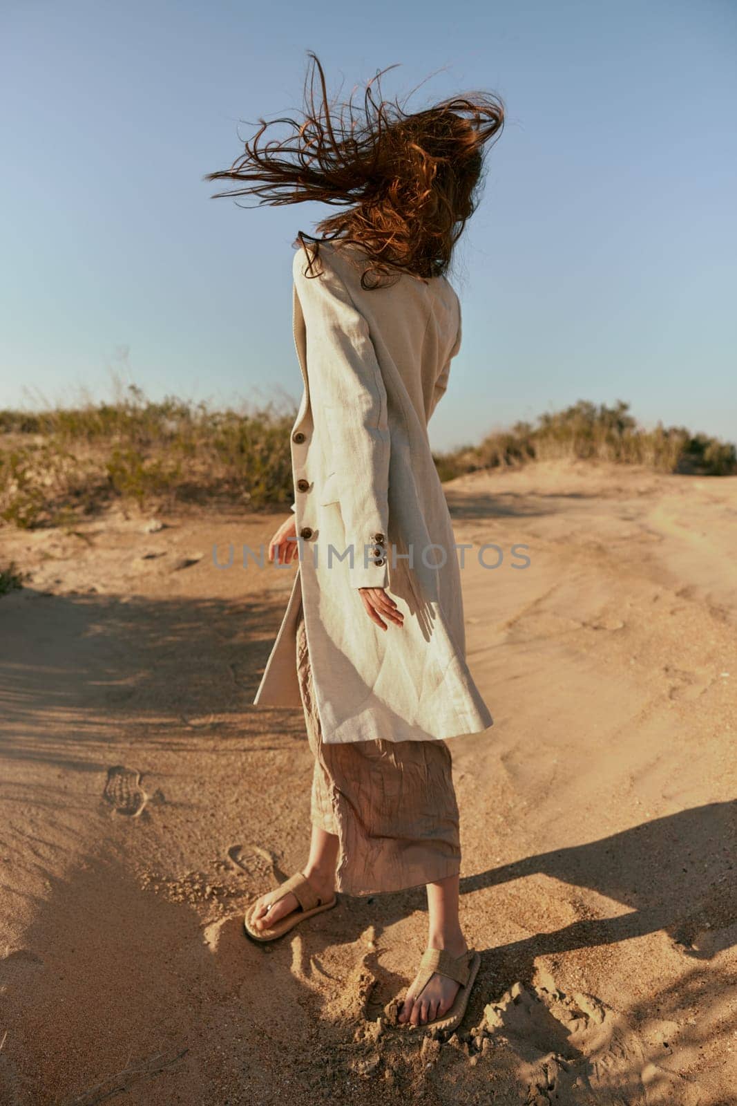 a woman in stylish, summer clothes stands in poses posing with her face covered by her hair. High quality photo