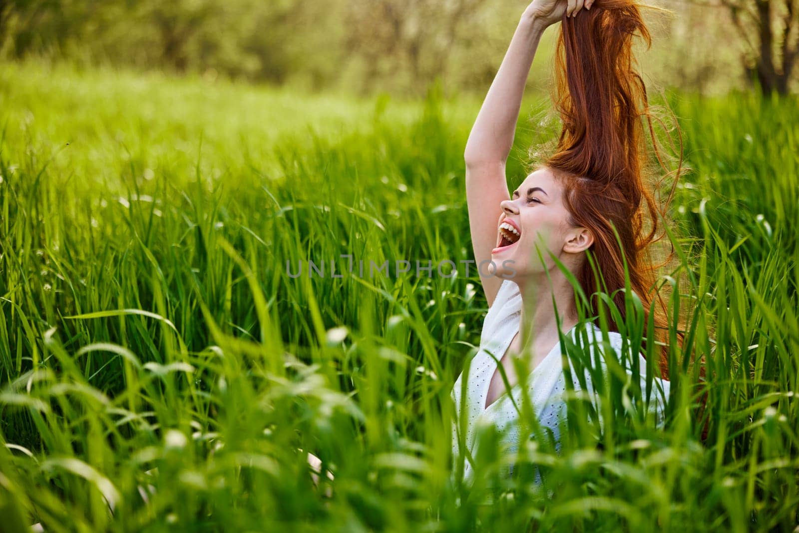 a red-haired woman stands in the tall grass, raising her oxen up and laughing widely with her teeth by Vichizh