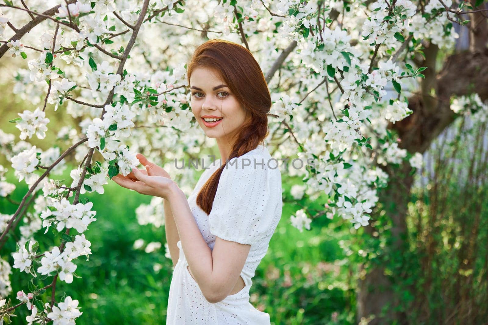 beautiful, cute woman touching flowers on a tree in the garden. High quality photo