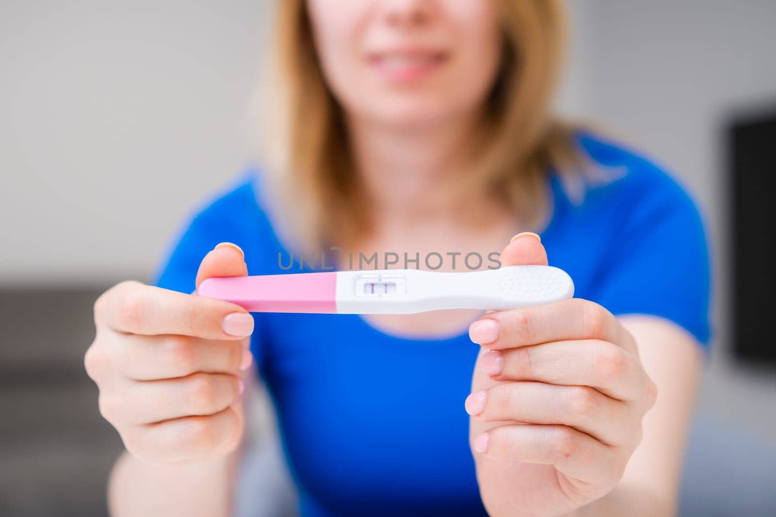 Blonde smiling woman holding a positive pregnancy test by vladimka
