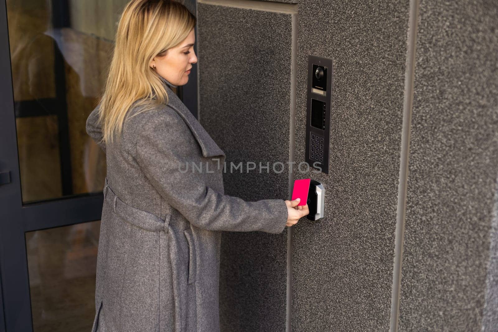 woman using intercom at building entrance. by Andelov13