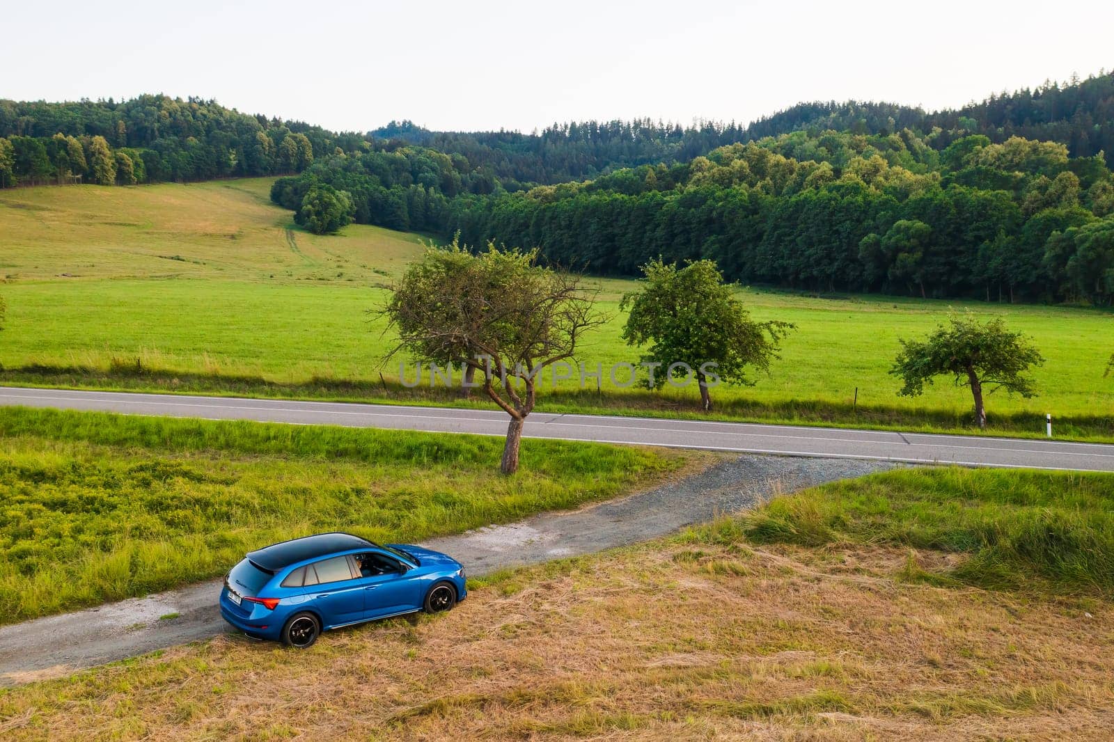 Blue Skoda Scala car standing on the countryside road with amazing view on the valley and lush trees, aerial view, August 2022, Dolni Morava, Czech Republic