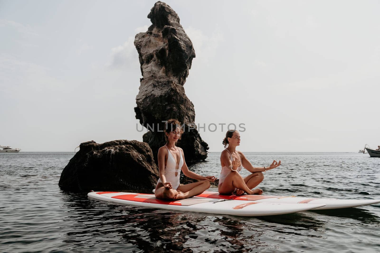 Woman sup yoga. Middle age sporty woman practising yoga pilates on paddle sup surfboard. Female stretching doing workout on sea water. Modern individual hipster outdoor summer sport activity