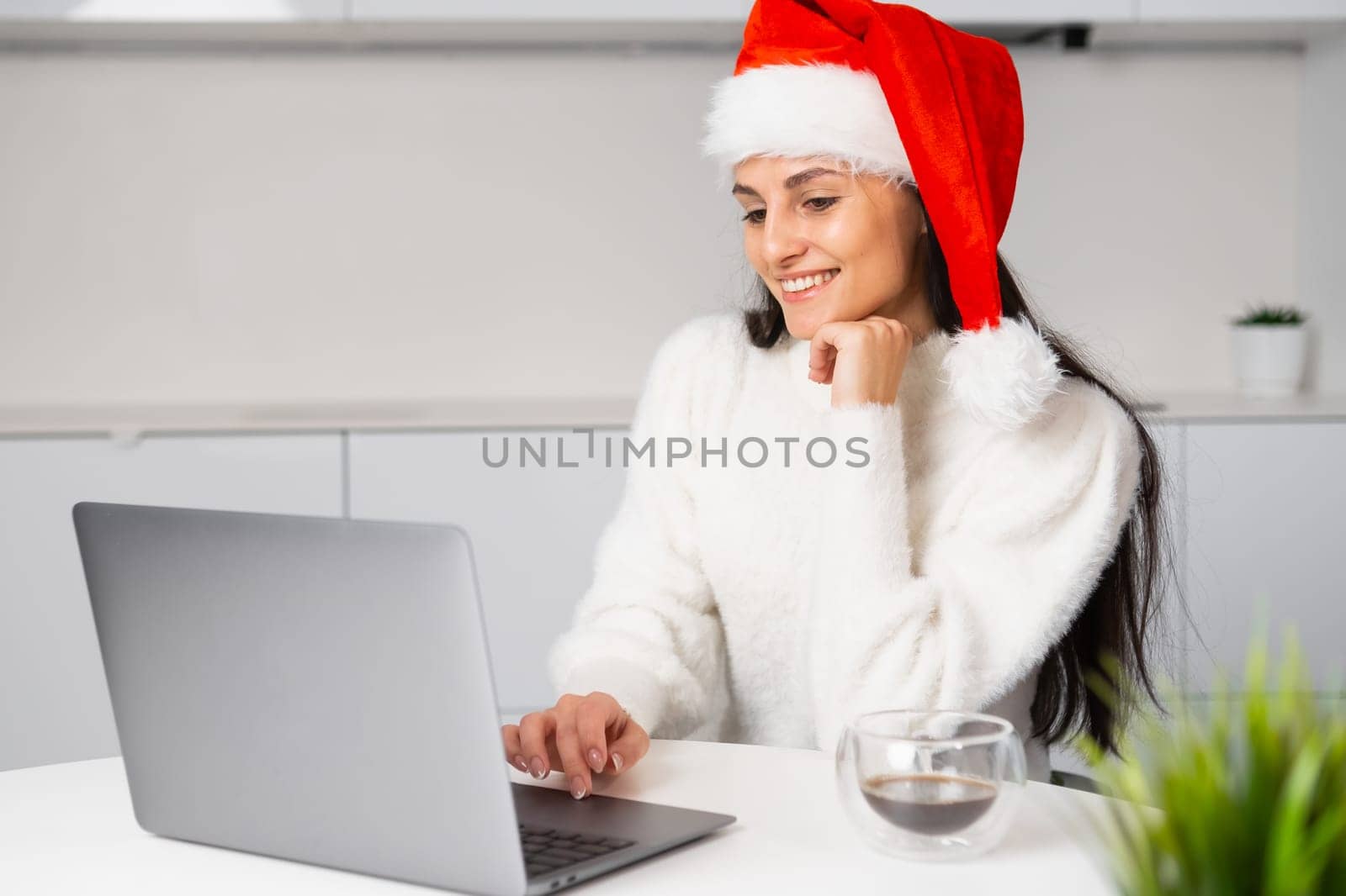 Young caucasian woman working remotely at home before Christmas. A woman has a video call at home.