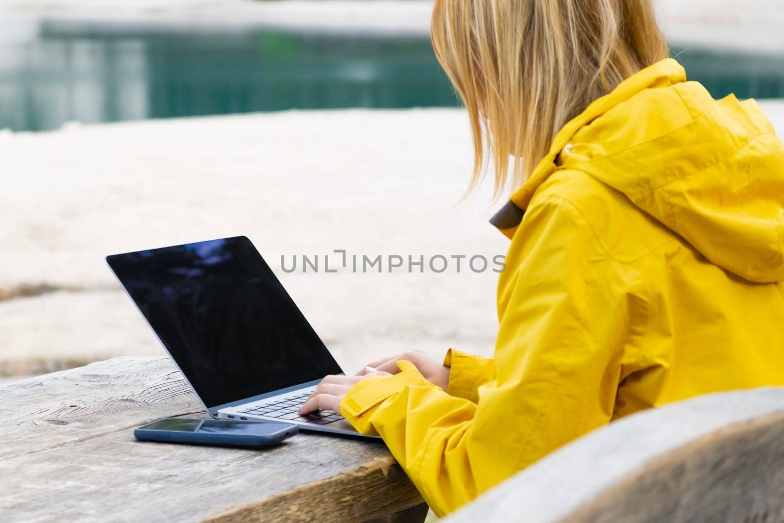 Remote worker relaxing near the lake and using laptop by vladimka