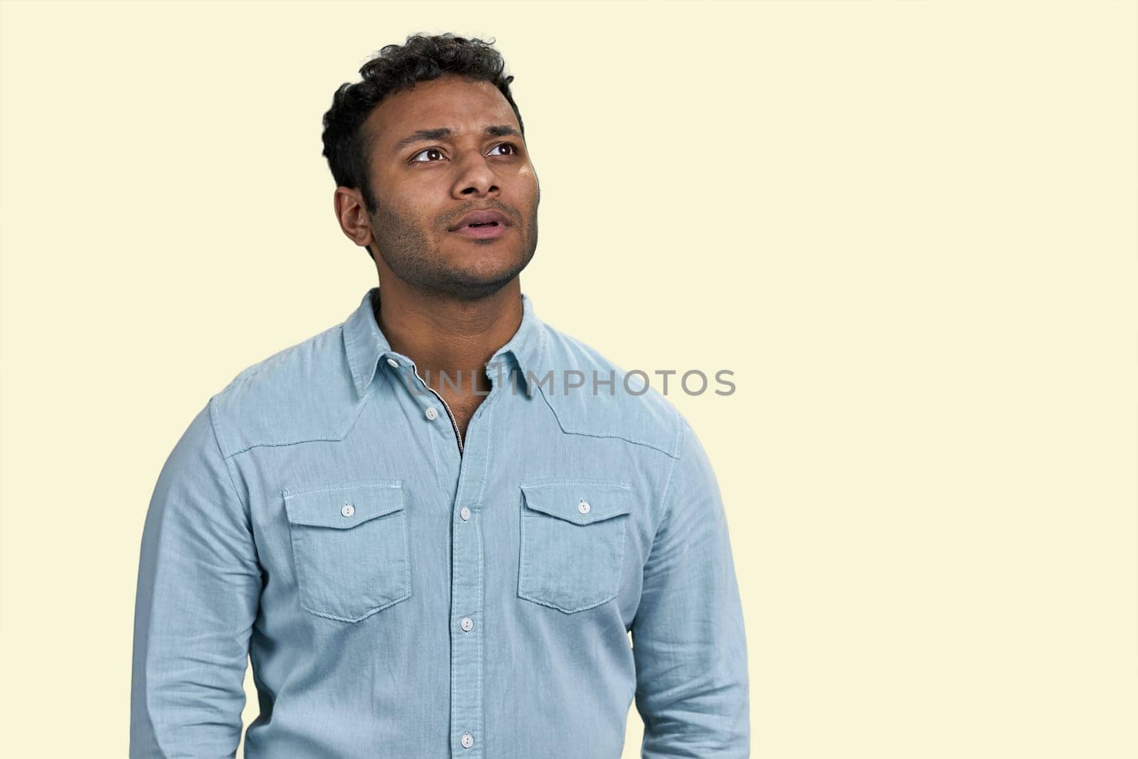 Portrait of a young thoughtful indian man is looking up. Thinking of new good opportunities. Isolated on white background.