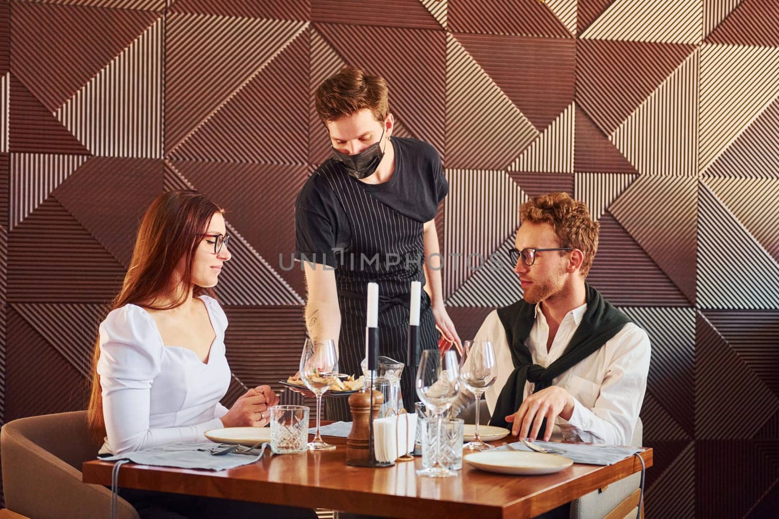 Young boyfriend with adult woman. Indoors of new modern luxury restaurant.