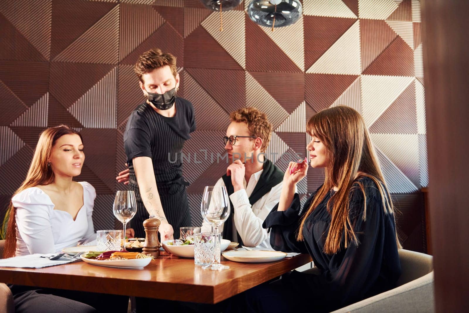 People have a dinner together. Indoors of new modern luxury restaurant by Standret