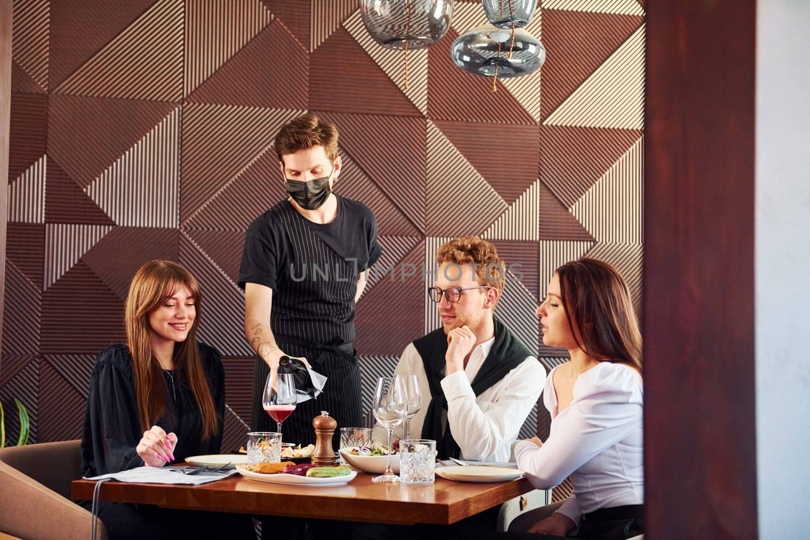 People have a dinner together. Indoors of new modern luxury restaurant.