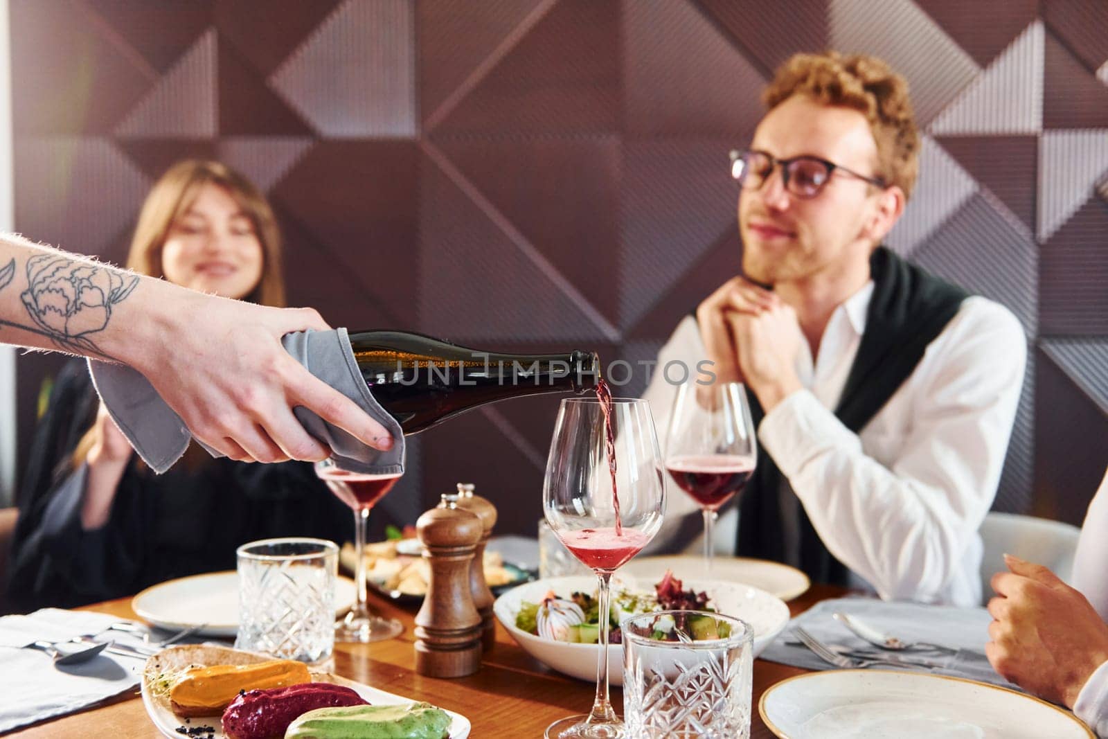 People have a dinner together. Indoors of new modern luxury restaurant.