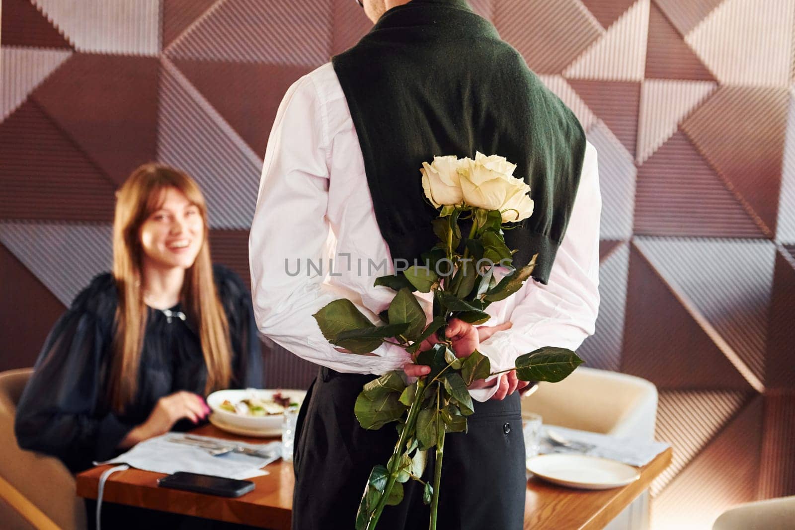 Waiter gives flowers to a woman. Indoors of new modern luxury restaurant by Standret