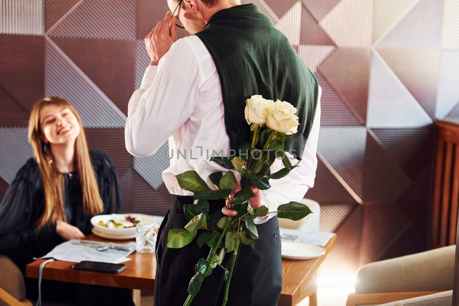 Waiter gives flowers to a woman. Indoors of new modern luxury restaurant.