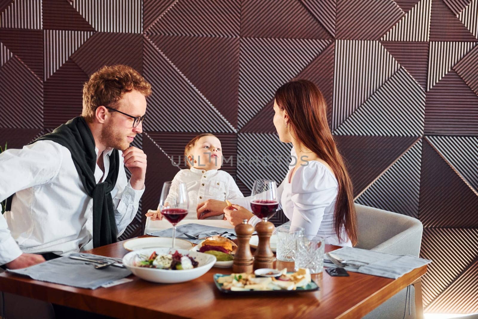 Young guy, woman and little boy. Indoors of new modern luxury restaurant by Standret