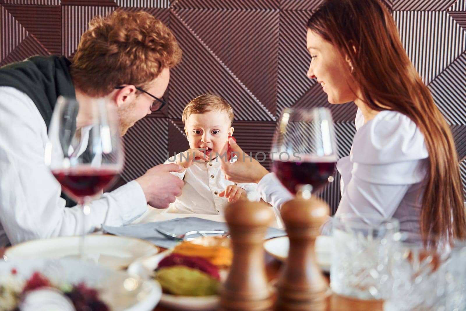 Young guy, woman and little boy. Indoors of new modern luxury restaurant.