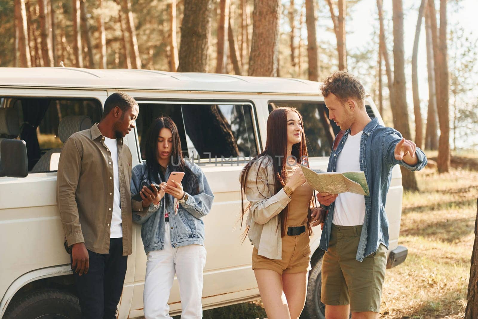 Standing near the car. Group of young people is traveling together in the forest at daytime by Standret