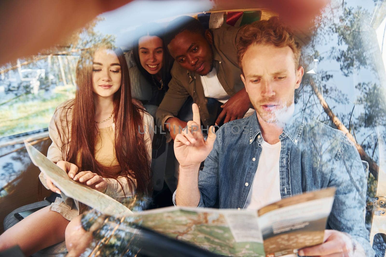 Looking for location by using map. Group of young people is traveling together in the forest at daytime.