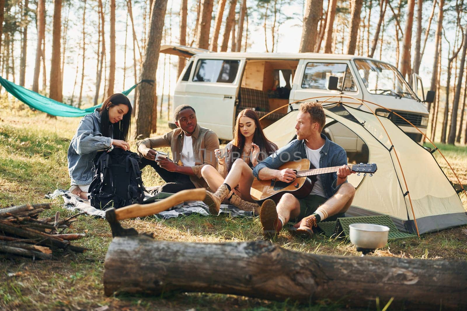 Camp and car. Group of young people is traveling together in the forest at daytime.