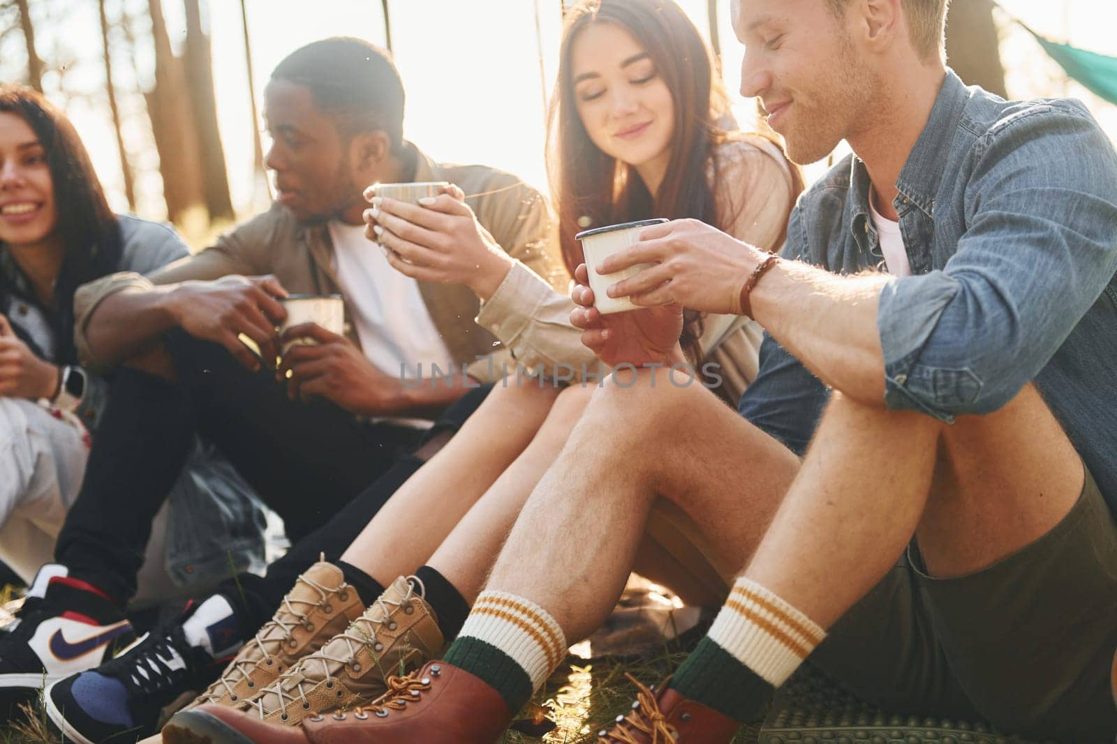 Talking with each other. Group of young people is traveling together in the forest at daytime by Standret