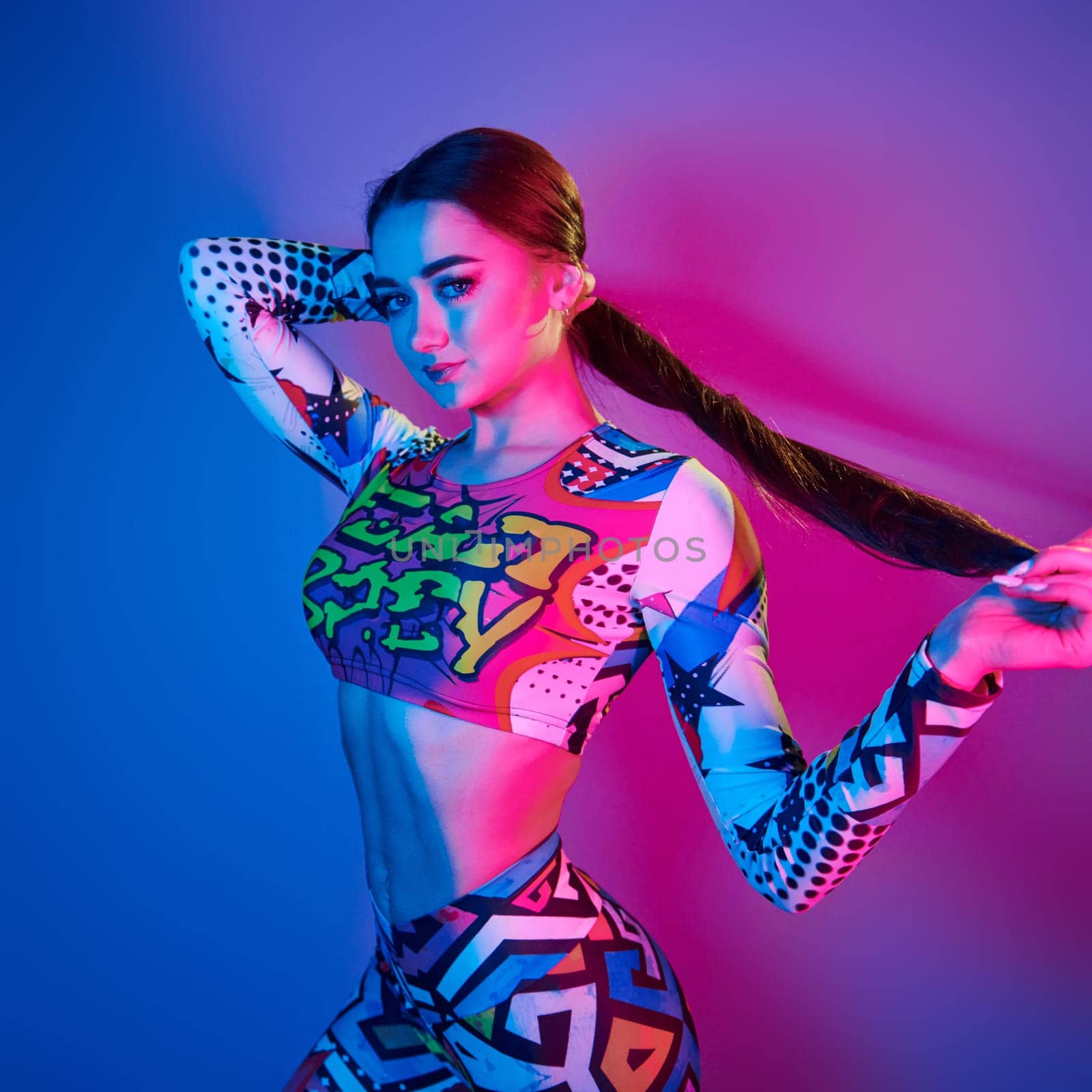 Fitness body type. Fashionable young woman standing in the studio with neon light.