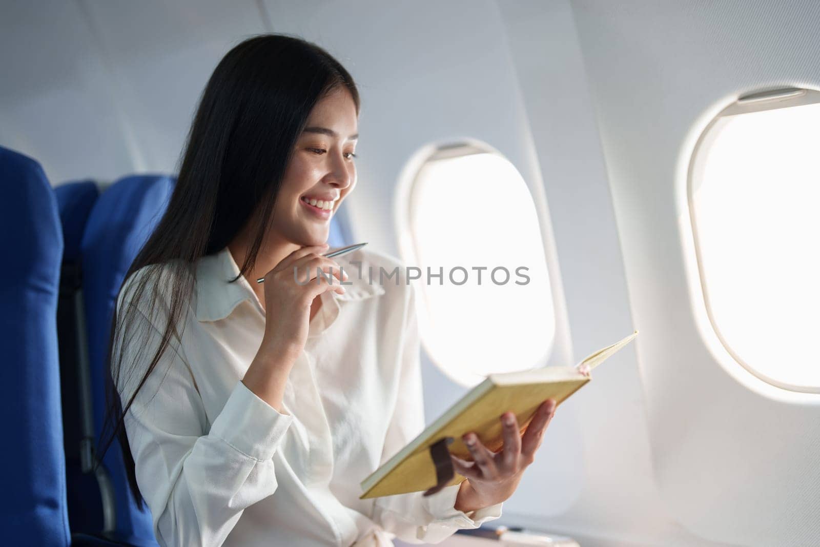 Asian business woman passenger sitting on business class luxury plane while working using notebook book while travel concept.