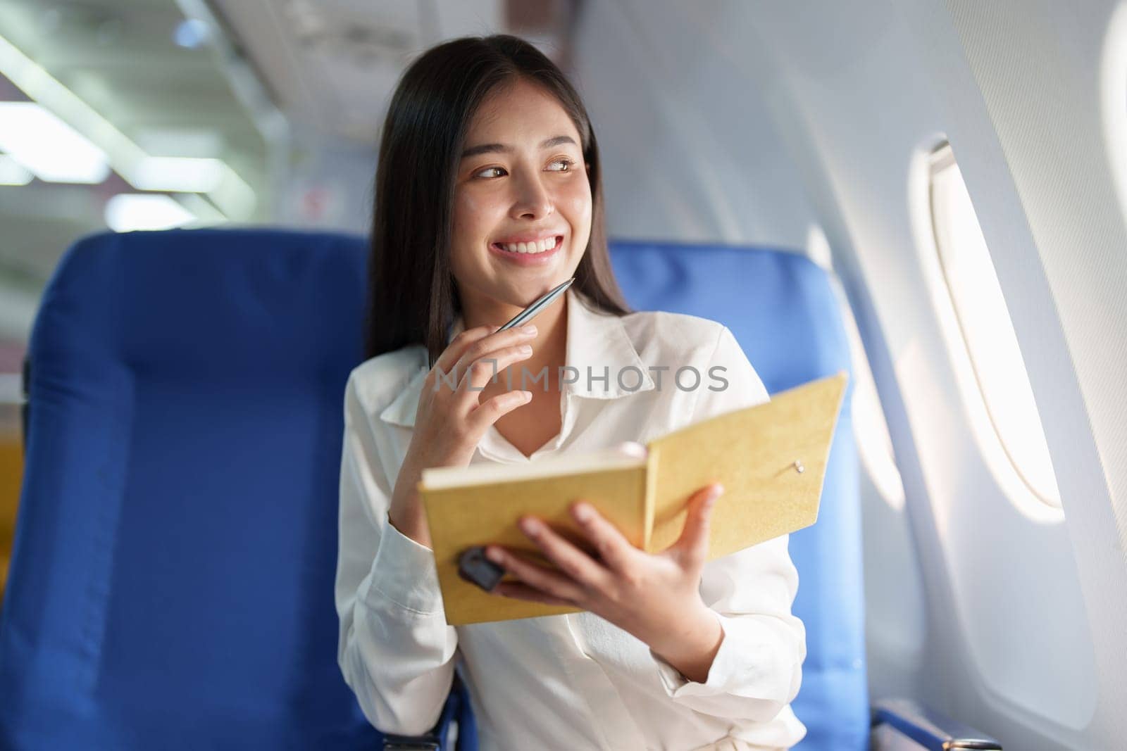 Asian business woman passenger sitting on business class luxury plane while working using notebook book while travel concept by Manastrong
