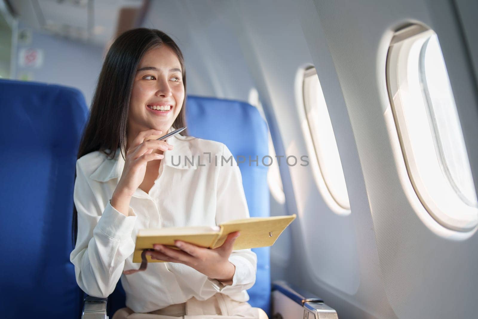 Asian business woman passenger sitting on business class luxury plane while working using notebook book while travel concept.