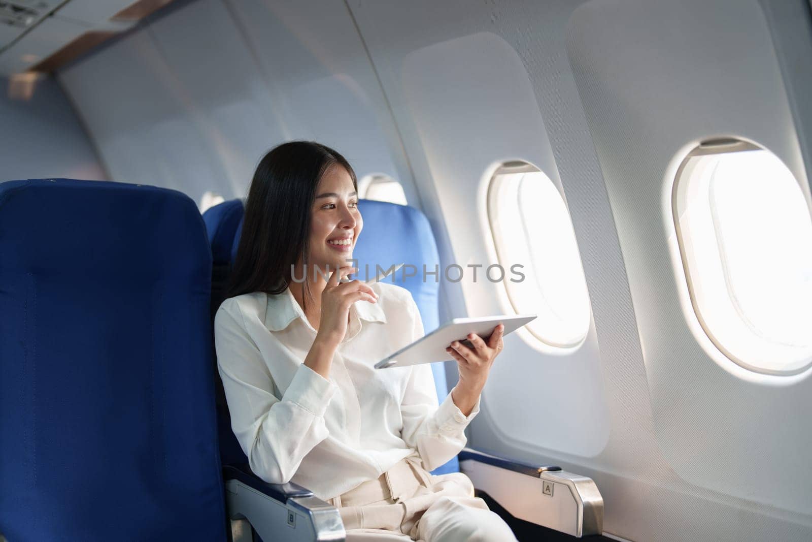 Asian attractive business woman passenger sitting on business class luxury plane while tablet computer while travel concept.