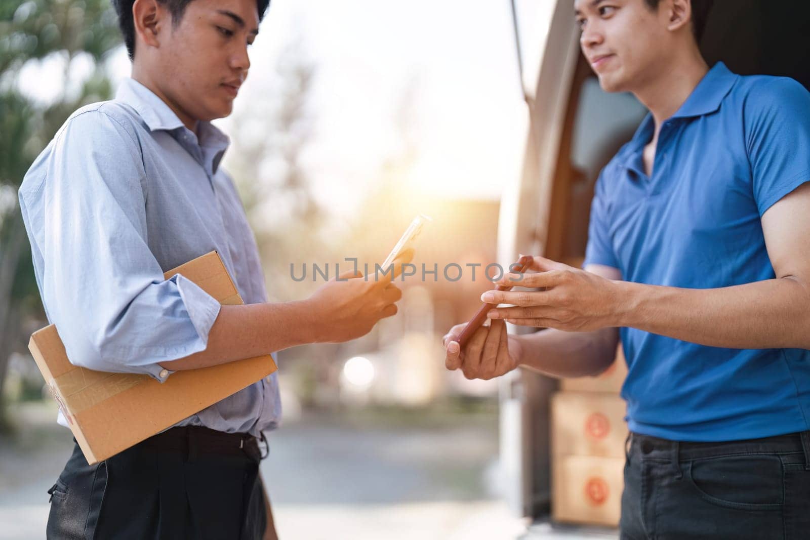 Logistic worker delivering cardboard boxes to recipient at home door. Scan QR Code. courier delivering parcel package concept by nateemee