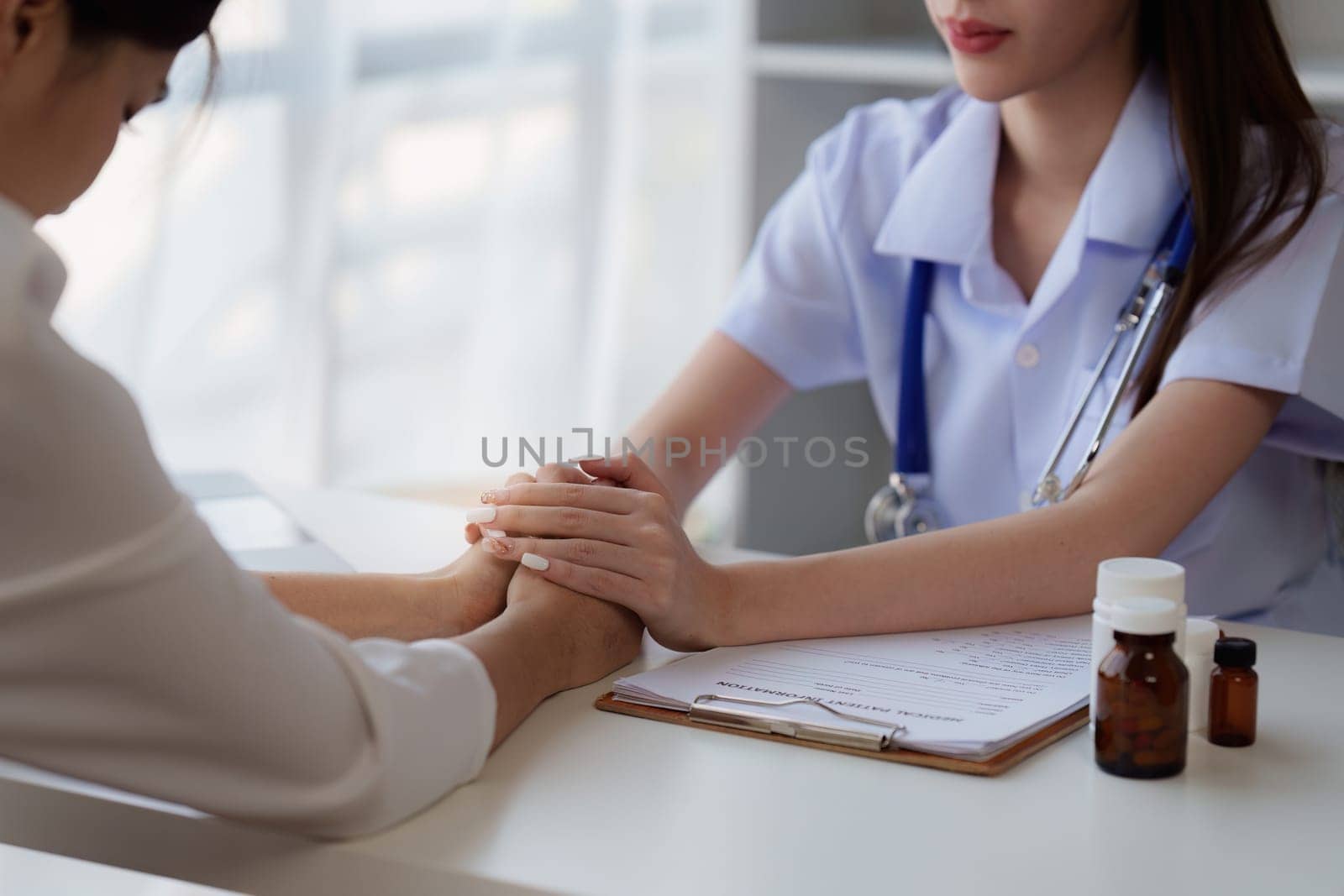 Doctor holding hand patient woman at clinic. health care, medical, healthy concept by itchaznong