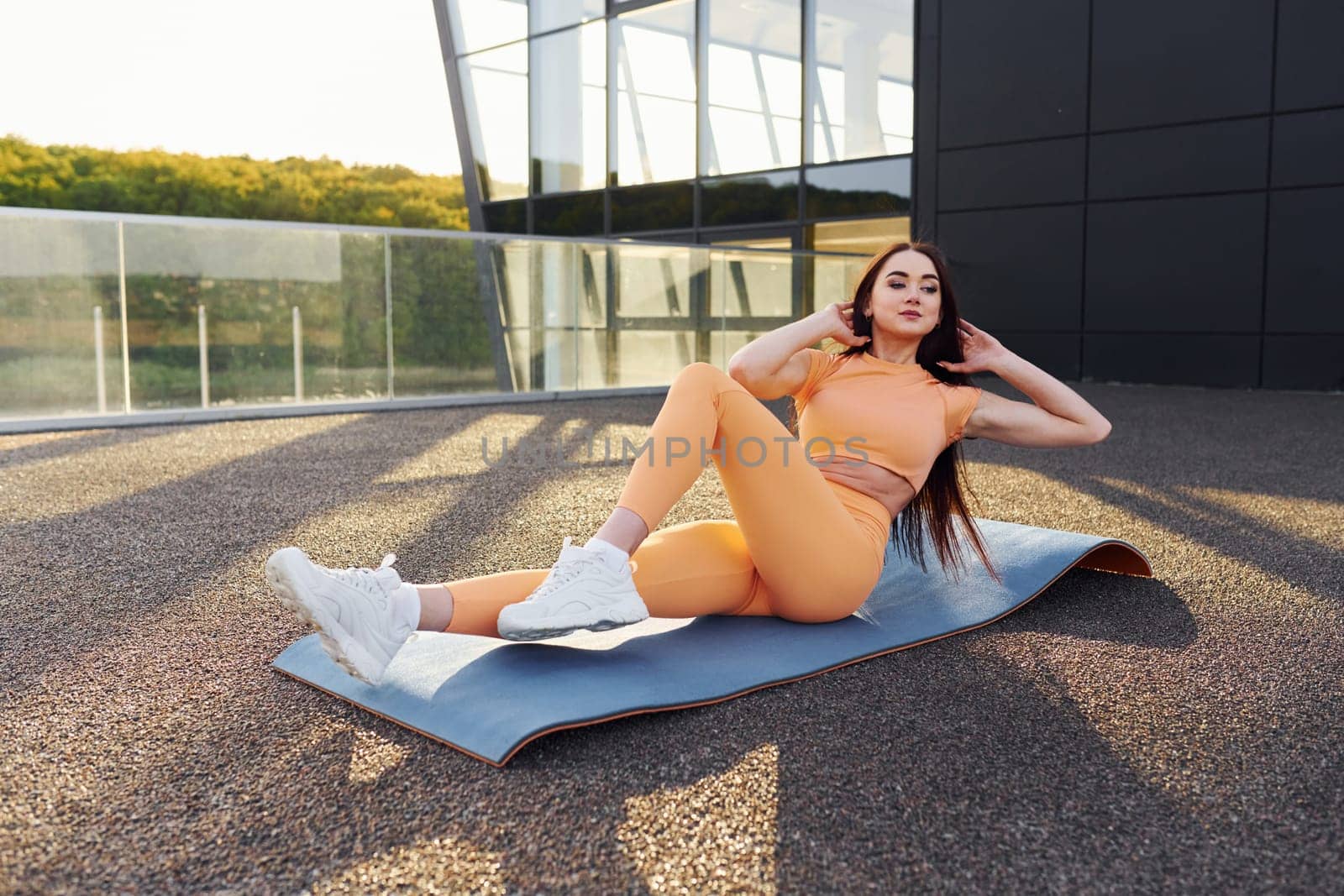 Modern exterior. Young woman in sportswear have fitness session outdoors by Standret