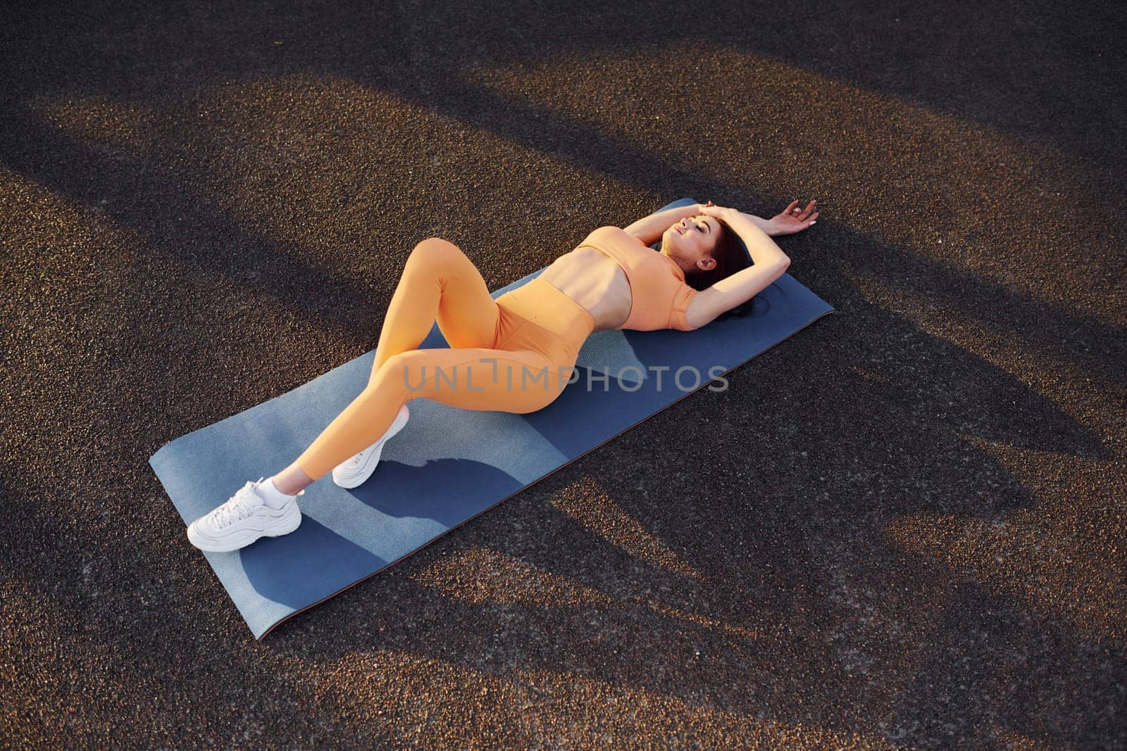 Top view. Leaning on the mat. Young woman in sportswear have fitness session outdoors by Standret