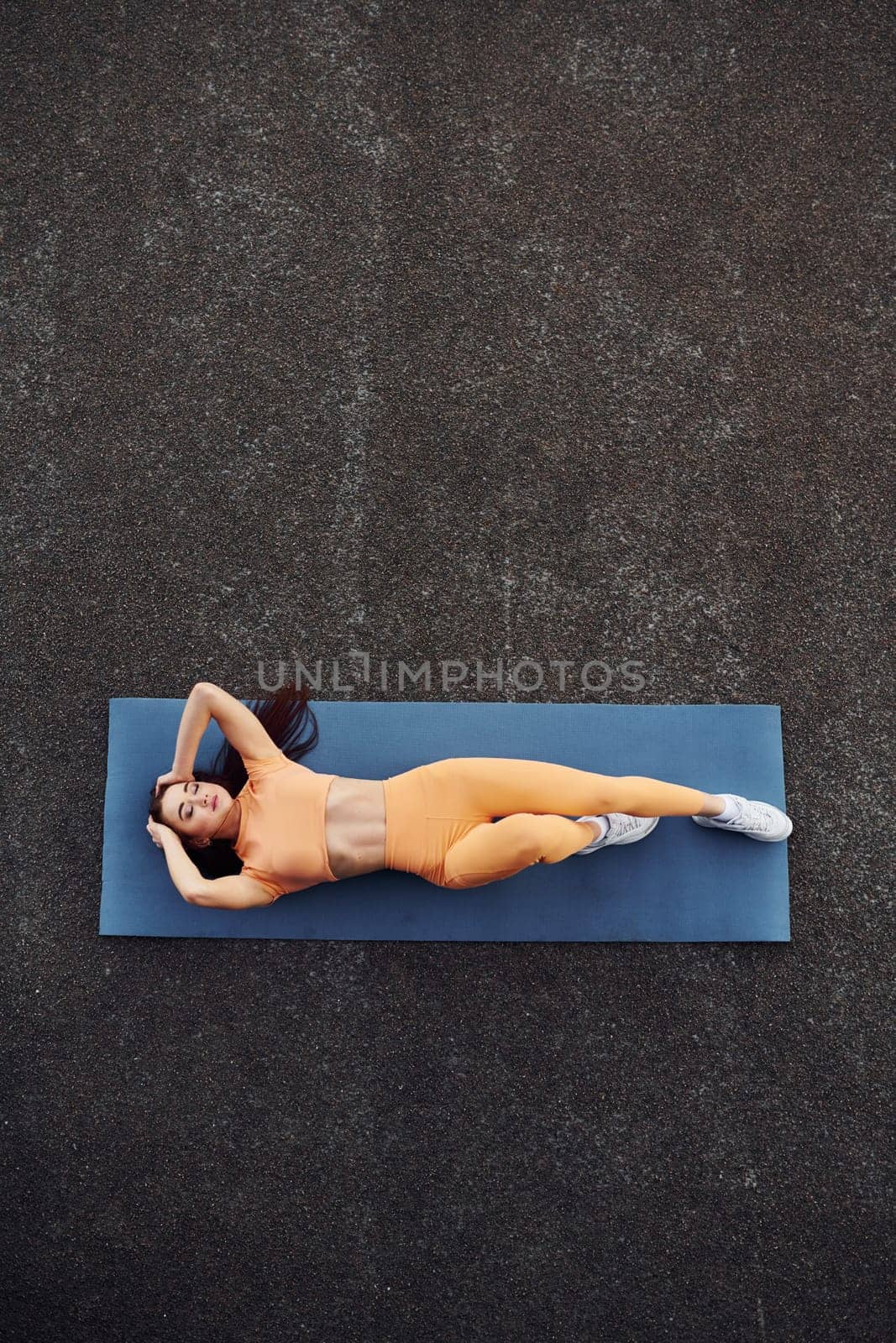 Top view. Leaning on the mat. Young woman in sportswear have fitness session outdoors by Standret