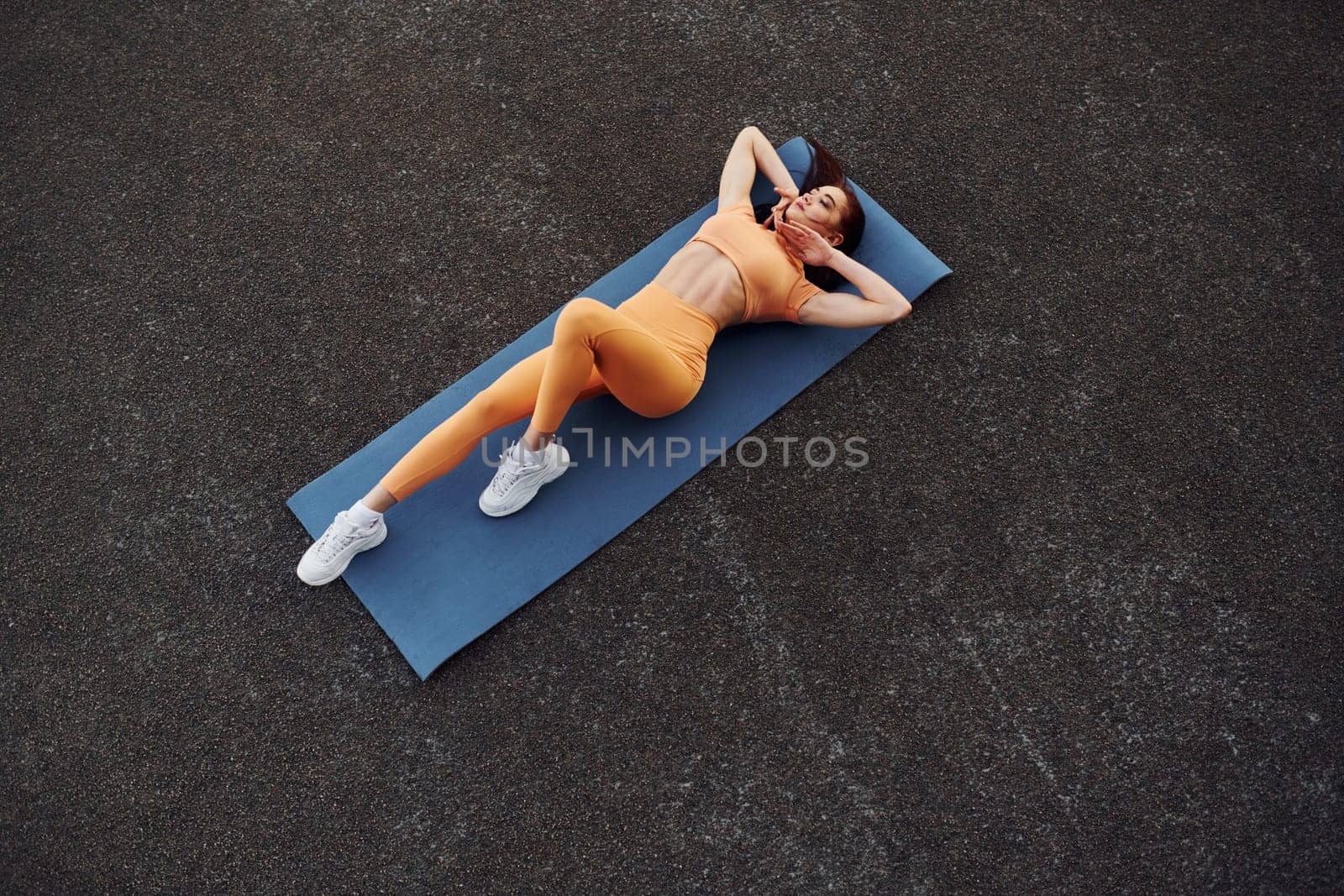 Top view. Leaning on the mat. Young woman in sportswear have fitness session outdoors by Standret