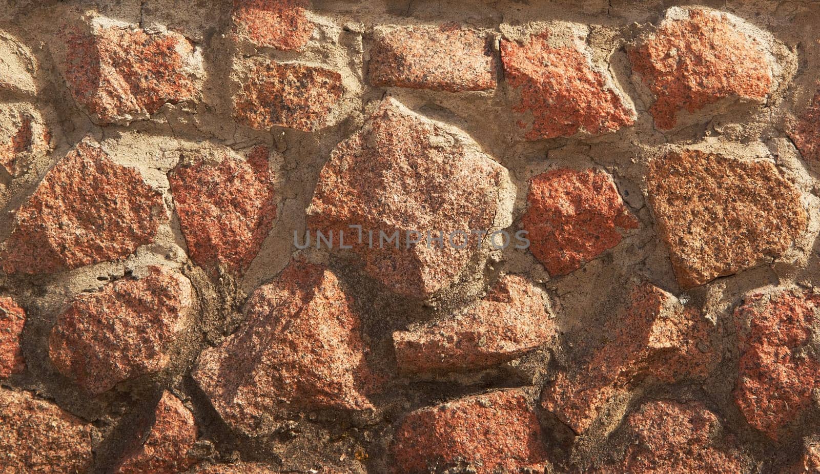 An ancient stone wall. Grunge background of a stone wall. The background of an old vintage stone wall. High quality photo