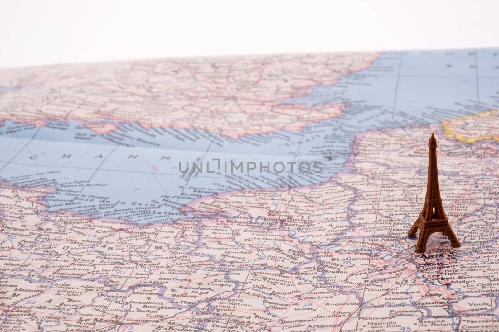 Close up detail of a miniature Eiffel tower on a colorful map of Paris, France with selective focus, background blur. High quality photo