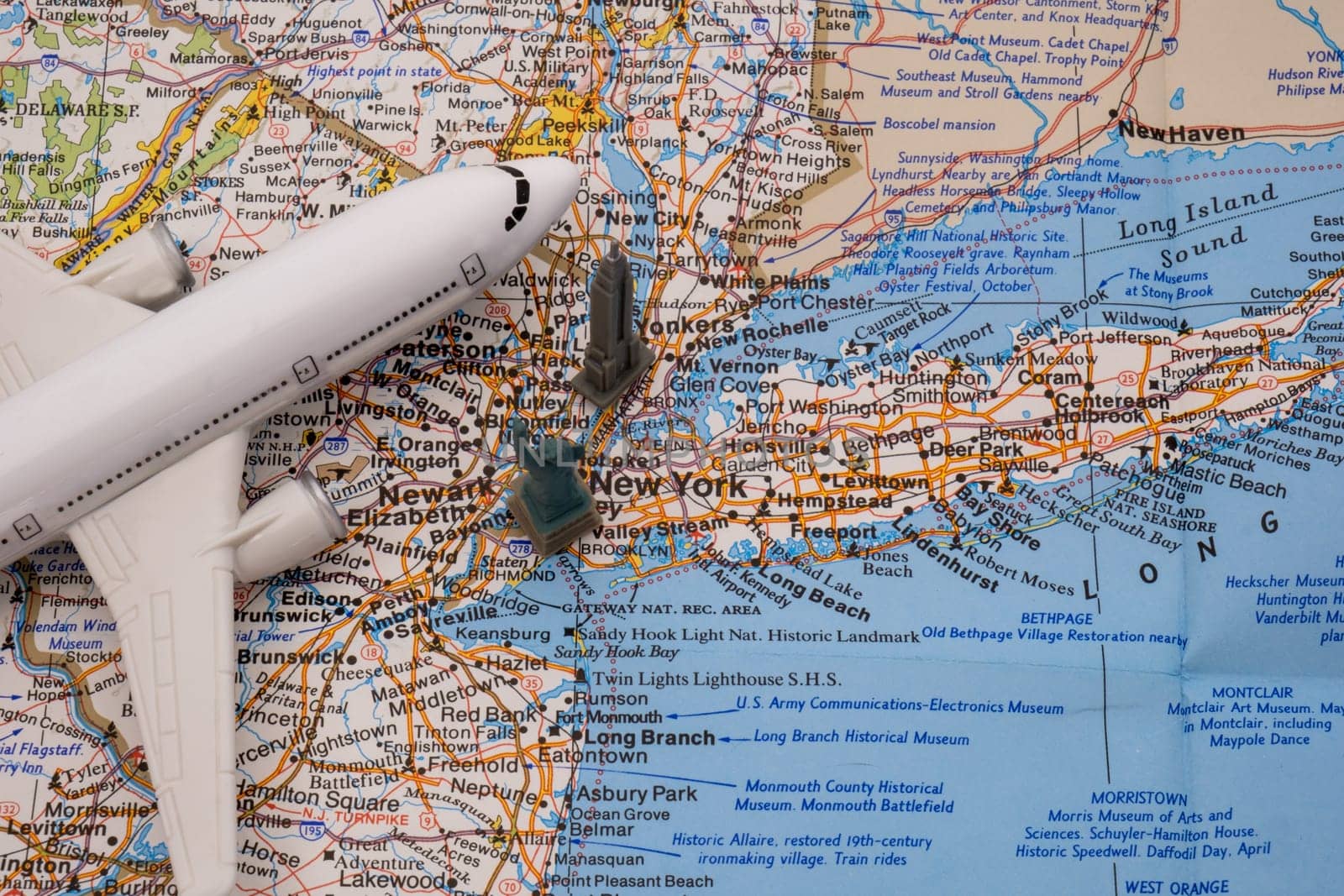 Close up detail of a miniature passenger plane on a colorful map of New York with a toy Empire State building, Statue of Liberty . High quality photo